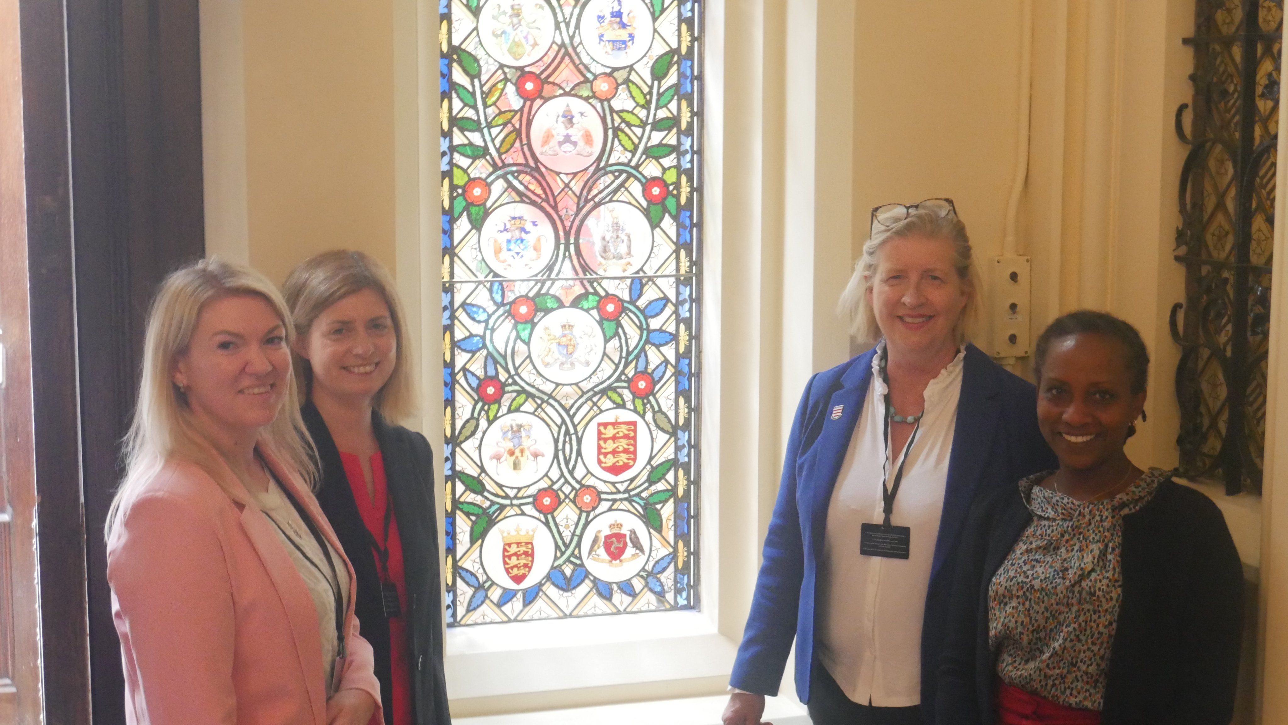 Jersey delegates next to the British Family Window displaying the three golden lions of Jersey's coat of arms