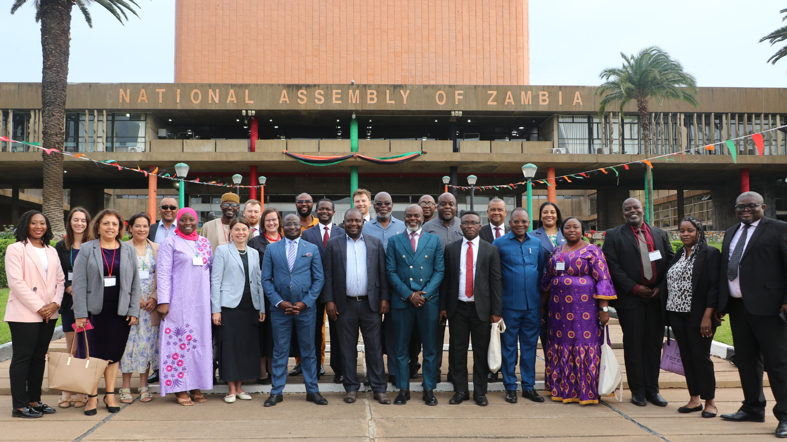 Delegates from across Africa, the UK, and St Helena stand outside the National Assembly of Zambia